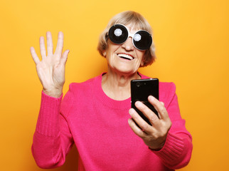 old grandmother is talking to her grandchildren by phone, smiling and greeting them.