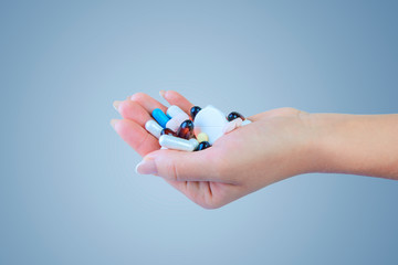 Close-up shot of a hand holding color pills on blue background