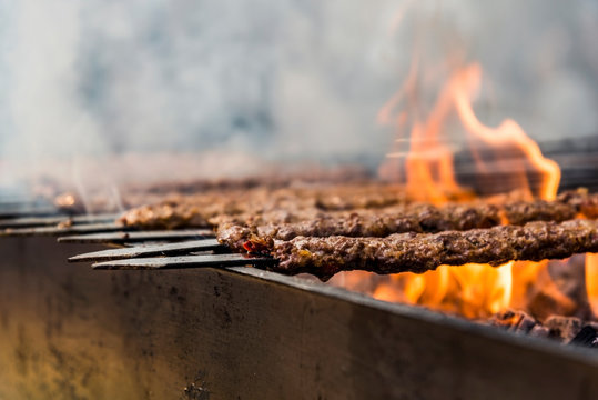 Traditional Adana kebab grilled on a bbq with orange coloured flame and smokes in Orange Blossom Carnival in Adana-Turkey