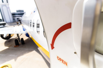 Open door of a plane parked while passengers disembark.