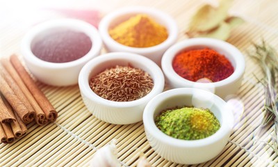 Various colorful spices in bowls on wooden table