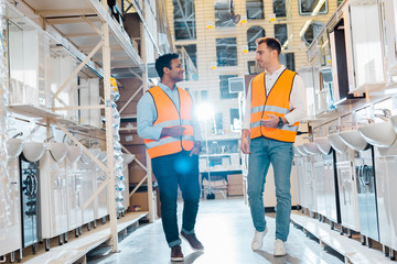 smiling multicultural warehouse workers talking in plumbing department
