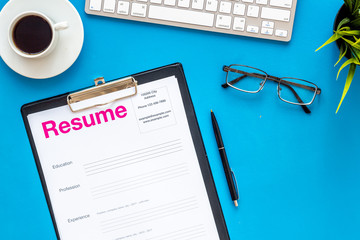 Review resumes of applicants set with coffee, glasses, keyboard blue work desk background top view