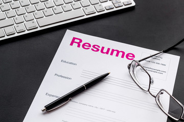 Create CV concept with pen, glasses, keyboard on black desk top view