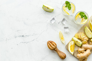 cold water with ice, ginger, mint, apple and lemon juice for summer healthy drink on white...