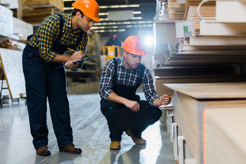 Obraz premium two multicultural colleagues in uniform and helmets working in warehouse