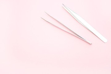 tools for Eyelash Extension Procedure. Two tweezers on pink background. copyspace mockup - Beauty and fashion concept