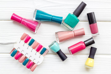 work desk at nail bar with nail polish and palette for manicure on wooden white background top view