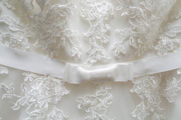 White tulle material with patterns in the shape of flowers and a bow in the middle.
