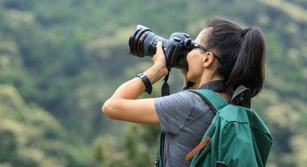 woman photographer taking photo on morning mountain forest