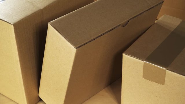 Pan over brown carton box parcels stacked on wooden office desk ready for shipment or just delivered
