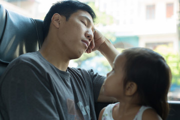Little girl looks at her tired dad while he's sleeping on the bus
