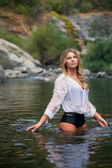 A young woman on vacation relaxining in a mountain creek on a hot summer afternoon.