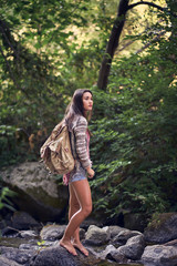 A teenage girl in a sweater and shorts hiking up a creek in a remote location in Northern California