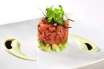 A healthy Ahi tuna tower with an avocado base on a white plate.