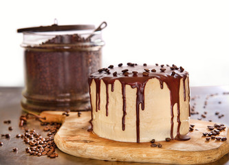 A chocolate coffee cake on a cutting board surrounded by coffee beans.