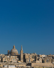 Fototapeta na wymiar Skyline of Valletta, Malta under blue sky, with dome of Basilica of Our Lady of Mount Carmel and tower of St Paul's Pro-Cathedral