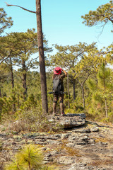 Woman traveler with backpack holding hat at mountains and Tropical forest. Female photographer outdoors in nature. Woman taking photo. Travel holiday relaxation conceptt, space for text