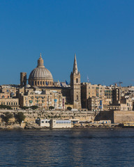 Fototapeta na wymiar Skyline of Valletta, Malta under blue sky, with dome of Basilica of Our Lady of Mount Carmel and tower of St Paul's Pro-Cathedral