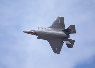 Very close top view of an F-35 Lightning II  against the cloudy sky - obrazy, fototapety, plakaty