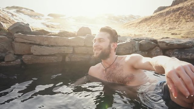 Happy man relax in geothermal hot pool in Iceland