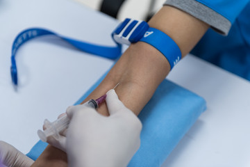 Close up nurse pricking needle into the patient arm for blood chemistry test.Laboratory with...