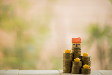 Save money on buying a house with coins on a wooden table on a blurred background.