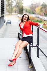 Young business woman sitting on the fence and relax in pause near the office and smile