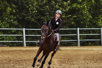Young woman jockey in white black dress and black boots  takes part in equestrian competitions.