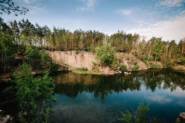 Lake on the background of rocks and fir trees. Canyon. The nature of autumn. Place for text and design. Landscape of an old flooded industrial granite quarry filled with water.