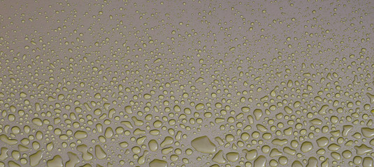 Yellow drops of water on brown metal window sill.