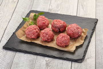 Raw meatball over wooden background
