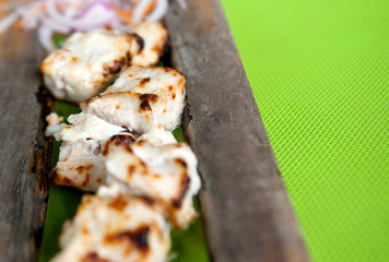 Grilled fish on wooden plate with curry sauce and onions