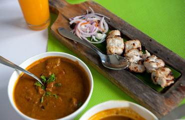 Grilled fish on wooden plate with curry sauce and onions