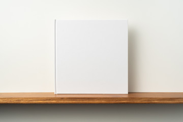white square notebook on bookshelf and white wall © voyata