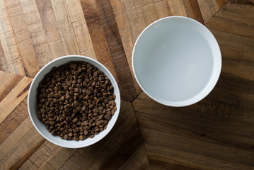 cat food dishes - top view of two bowls of dry cat food and water standing on a wooden table