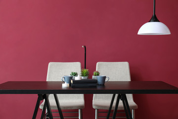 Table and chairs near color wall