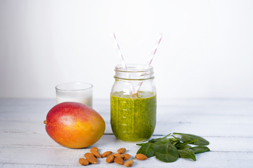Components of healthy Green Reach Vitamins Smoothie with baby leaf spinach, mango, almond milk and strawberry