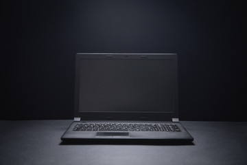 Black laptop on the black office desk. Technology concept