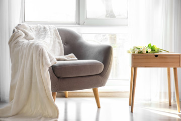 Comfortable armchair and table with fresh tulips near window in room