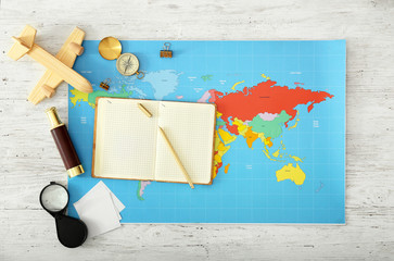 World map with notebook and travel accessories on white table