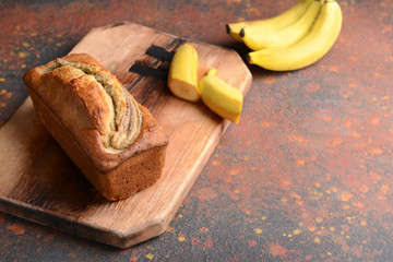 Wooden board with tasty banana bread on table