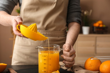 Woman preparing orange juice in kitchen
