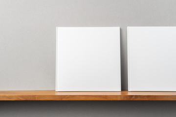 2 white square notebook on bookshelf and grey wall © voyata