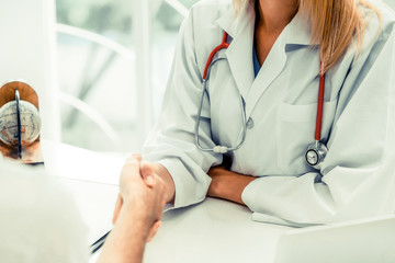 Woman doctor doing handshake with male patient in hospital office room. Healthcare and medical...