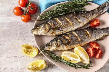 Plate with tasty cooked fish on light table