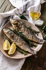 Plate with tasty cooked fish on wooden table