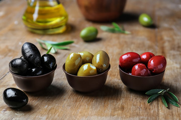 Bowls with tasty olives on wooden background