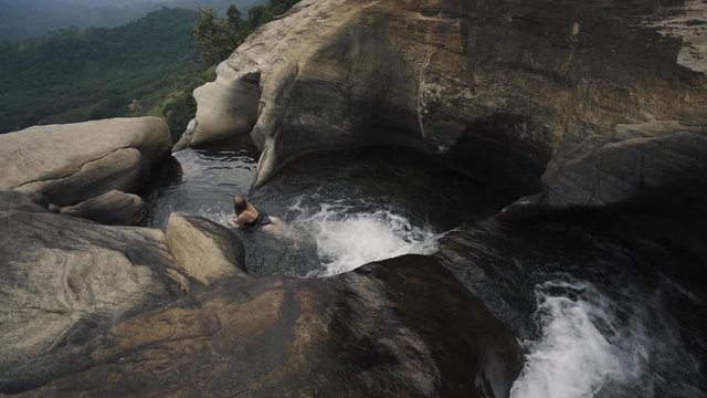 Woman swimming in one of the many natural pools of Sri Lanka's second highest waterfall "Diyaluma Waterfall".