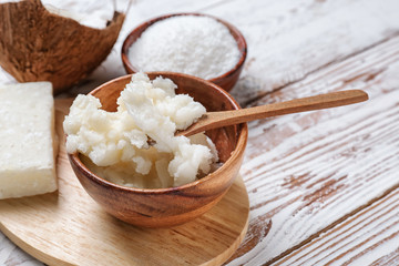 Bowl with coconut oil on white wooden background